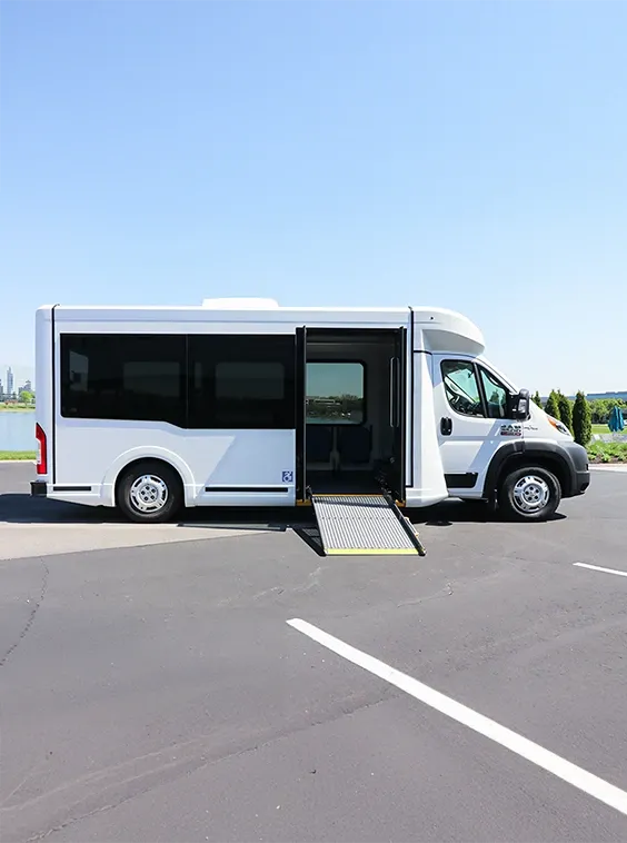White shuttle accessible bus with blue sky and trees at a parking lot