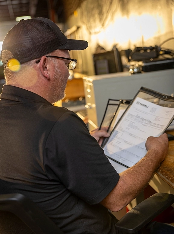 a mechanic looking at paperwork at a desk area