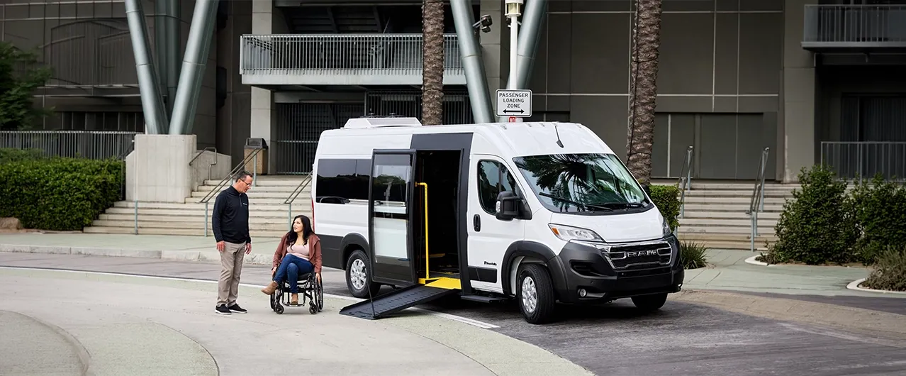 wheelchair van parked in front of building with a woman in a wheelchair and a man helping her