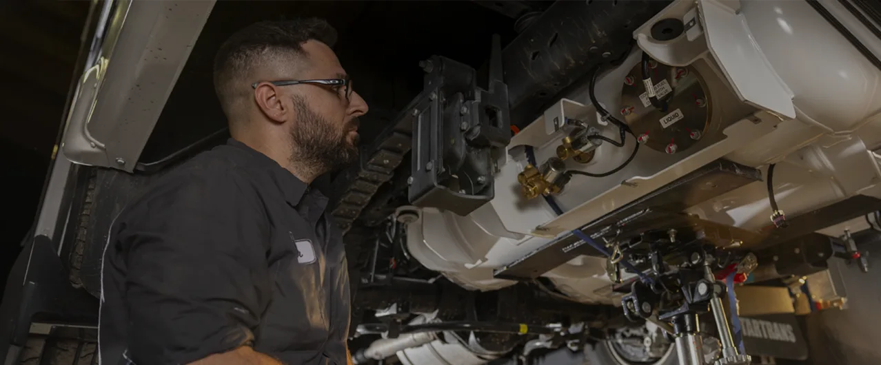 a mechanic taking a look underneath a vehicle at the parts