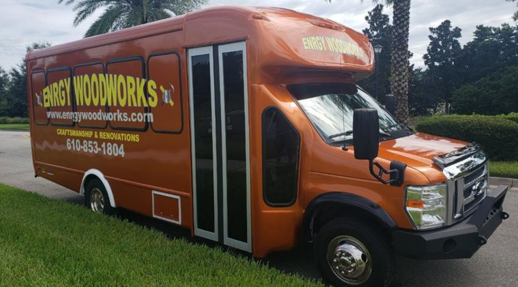 An orange bus converted into a mobile business parked on the side of the road.