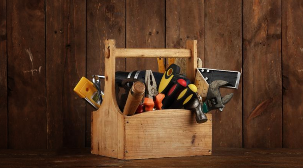 A wooden toolbox filled with tools displayed on a wooden background for bus maintenance.