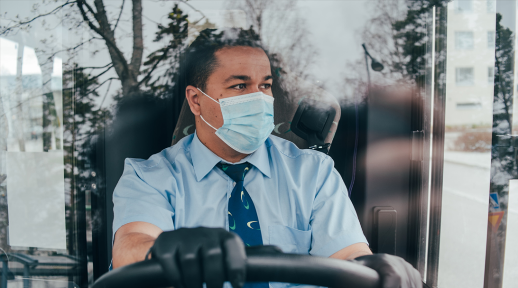 A bus driver wearing a disposable face mask.
