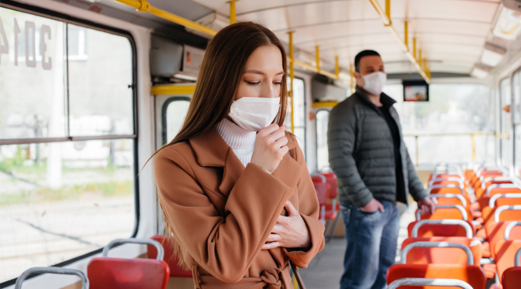A woman wearing a disposable face mask on a city bus
