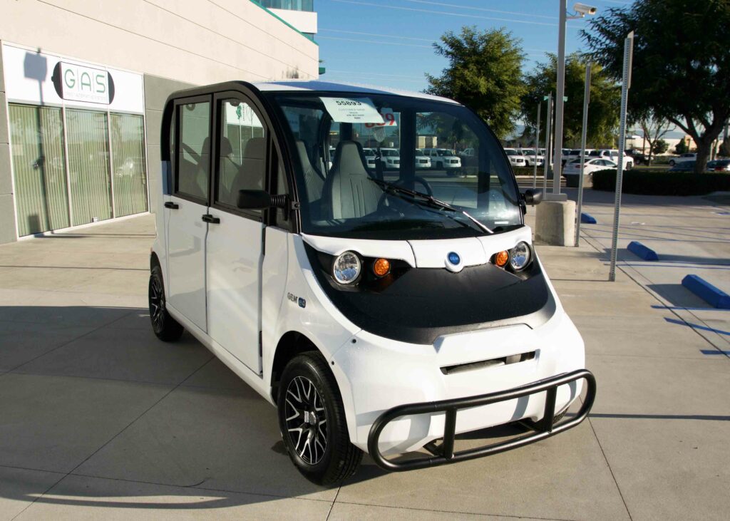 A white electric car parked in front of a building.