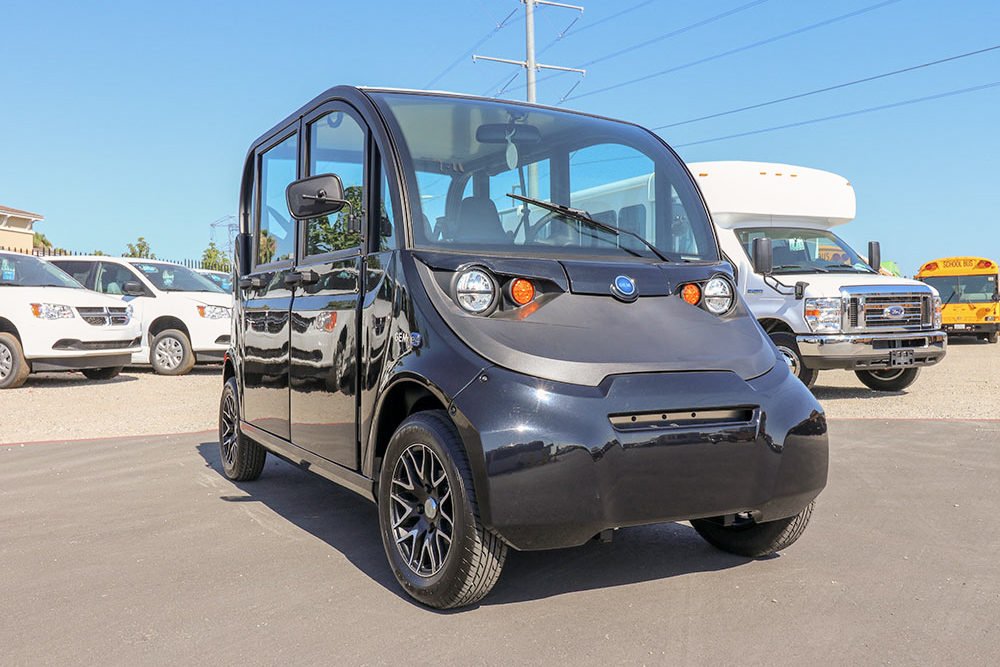 A black GEM E4 electric vehicle parked in a parking lot.