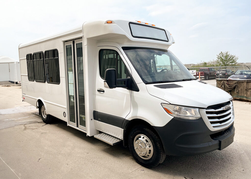 A white shuttle and tour bus parked in a parking lot.