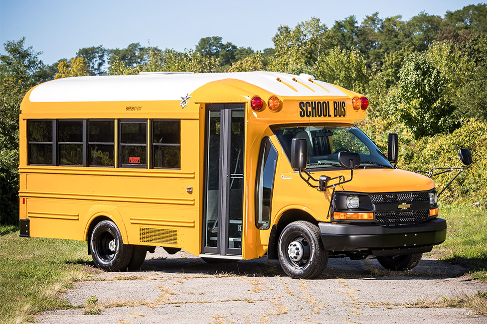 A yellow, Trans Tech SST school bus parked on a road.