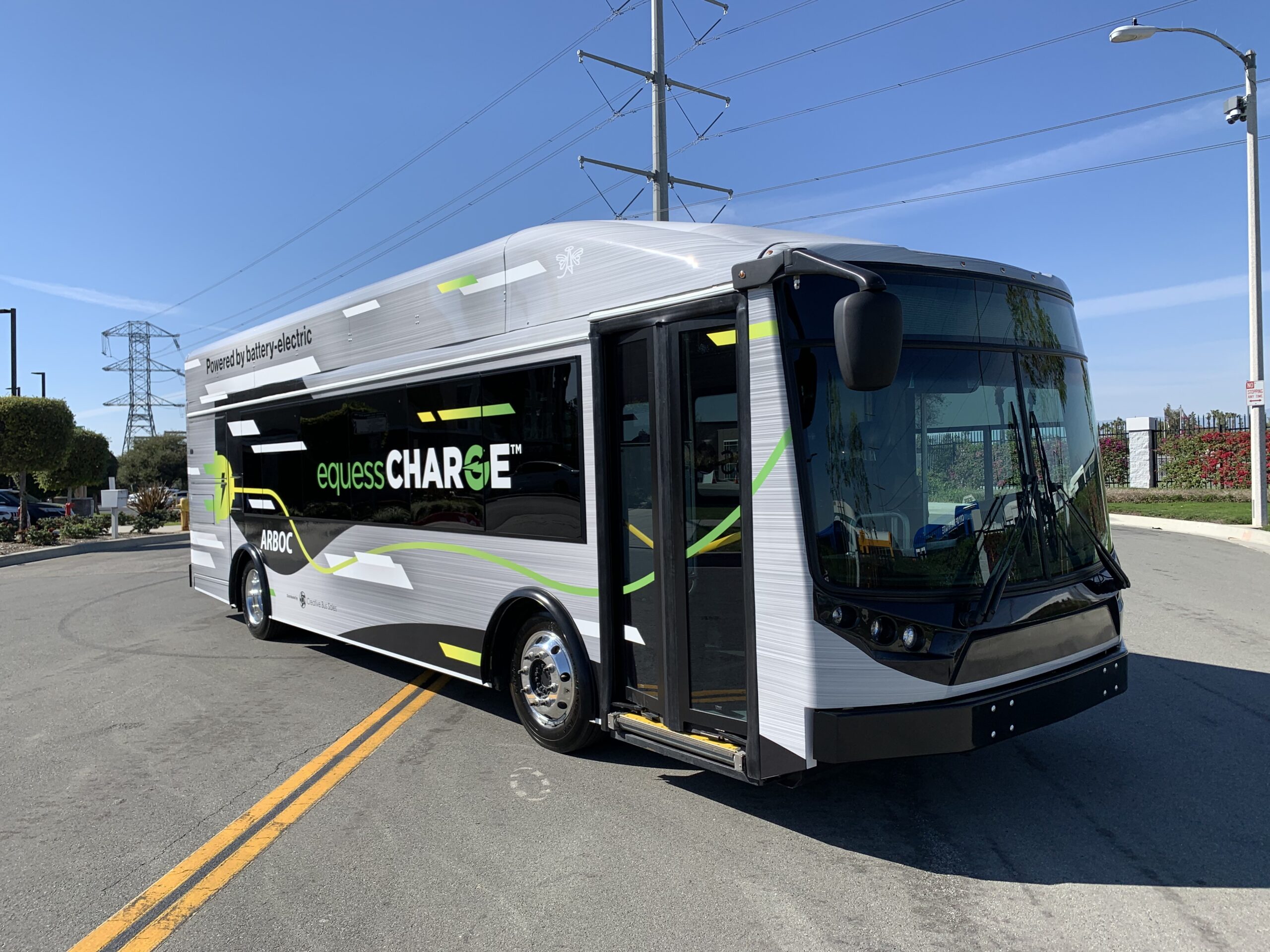 An electric ARBOC bus is driving down a street.