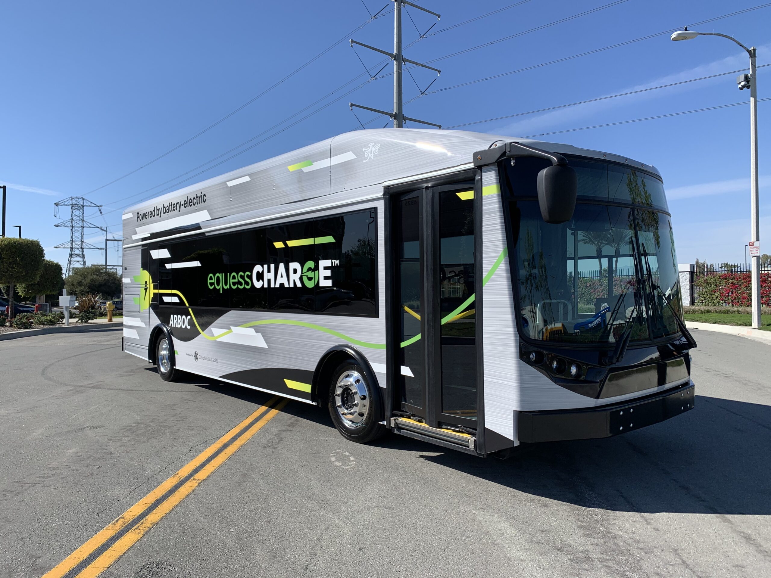 An electric bus, the 2021 ARBOC Equess CHARGE, is driving down a street.