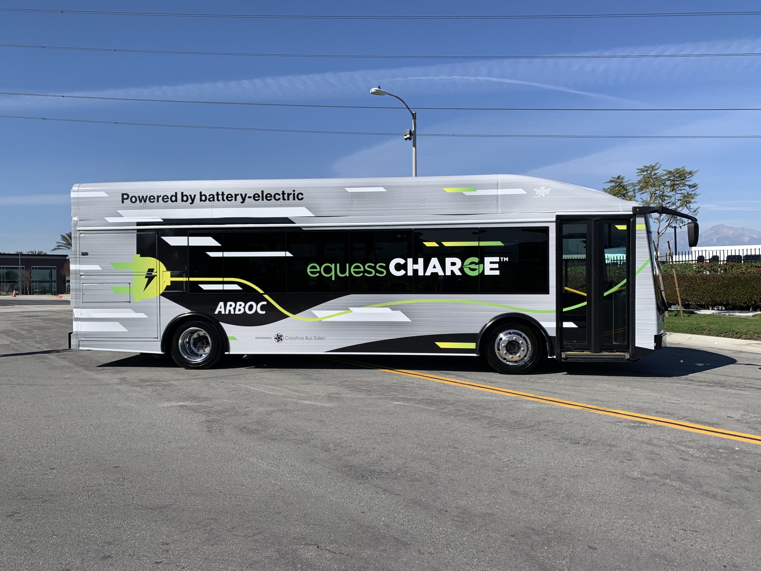 A 2021 white and black ARBOC Equess CHARGE electric bus parked in a parking lot.