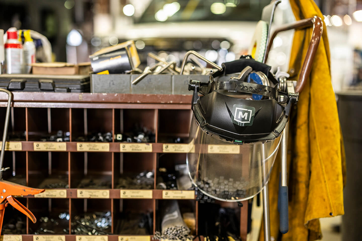 Welding helmets and tools on a shelf in a workshop.