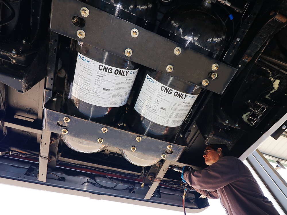 A man is installing an alternative fuel program under the truck hood.