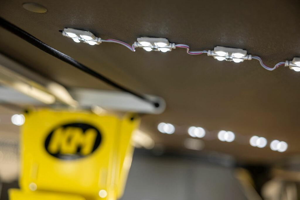 A yellow and white LED light is hanging from the ceiling of a cargo van.