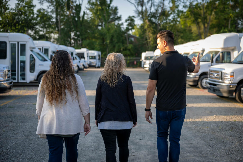Three people walking in front of a row of white vans.
