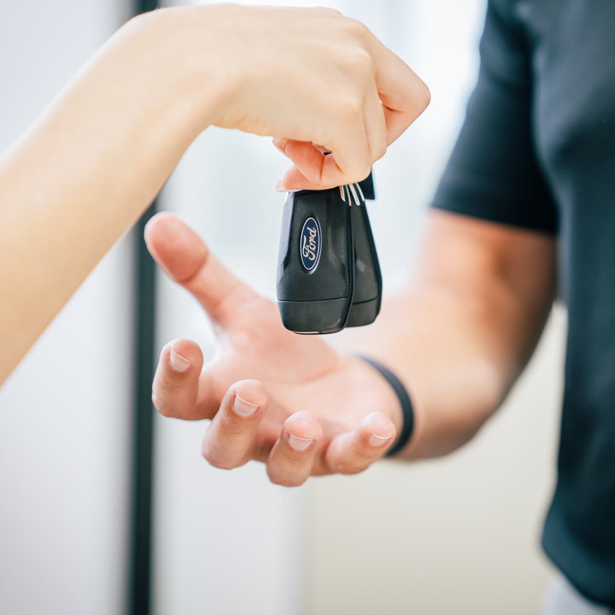 A person handing a car key to another person at home.