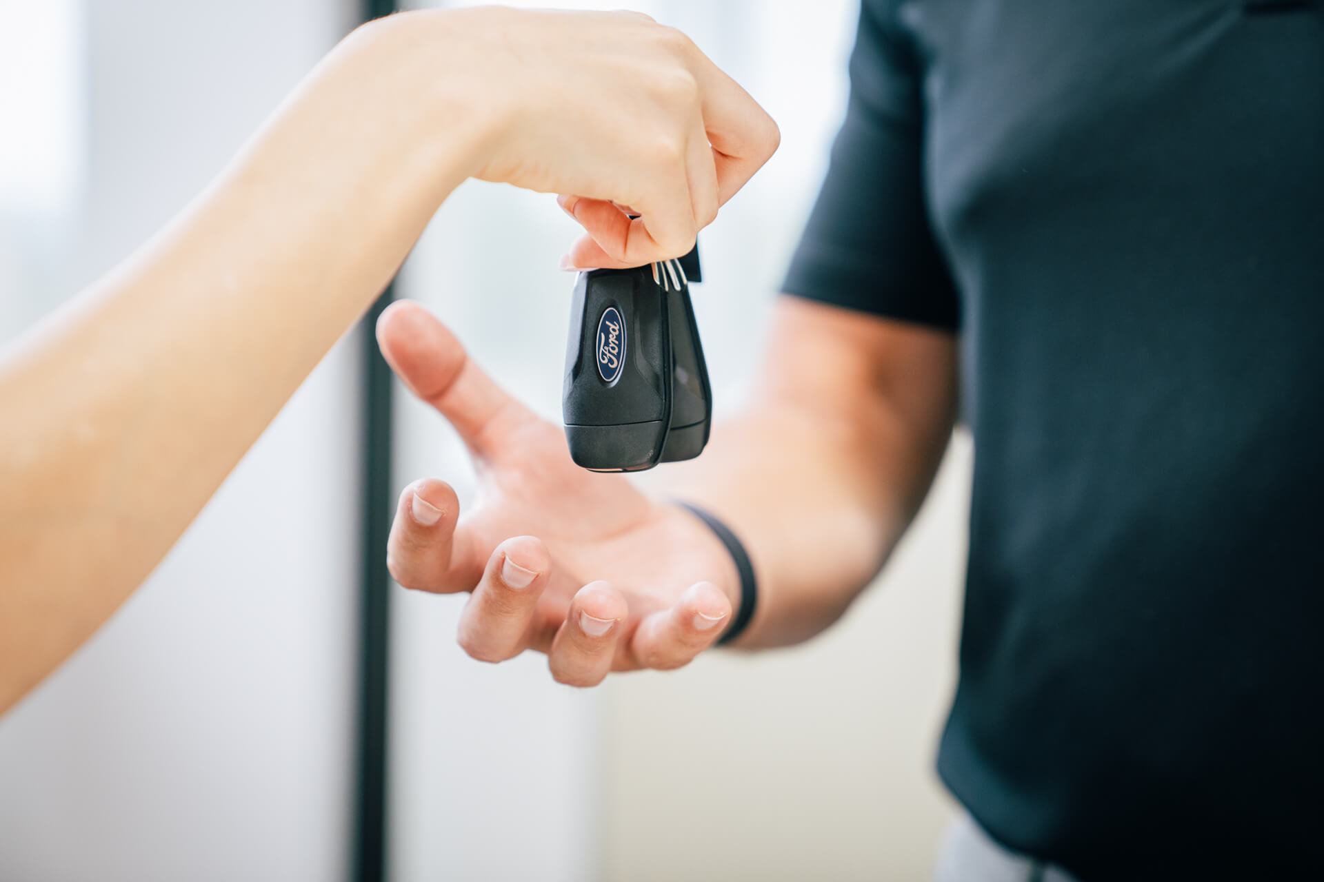 A person transferring a car key to another person during a model photography shoot.