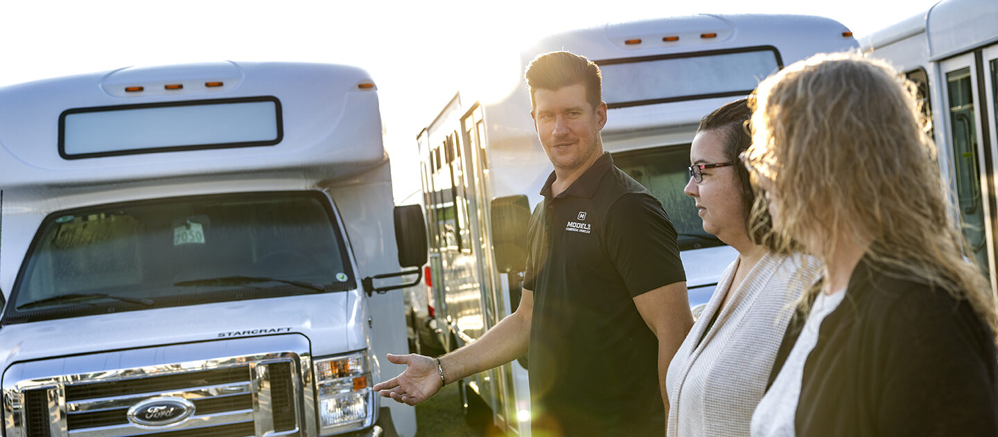 A model 1 employee showing a couple of buses at a trade show.