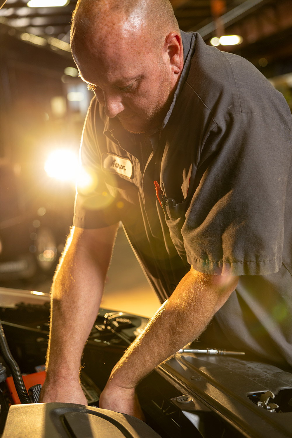 A mechanic performing maintenance and repairs on a car in a garage.