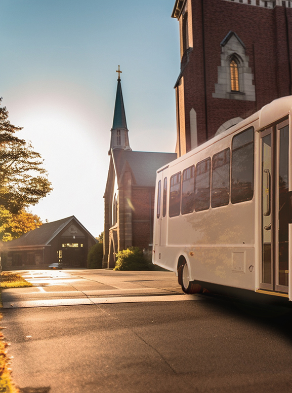 White bus driving in front of an old church