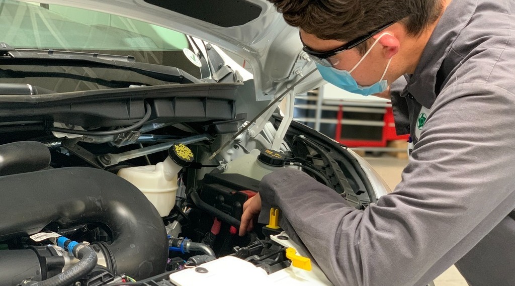 A mechanic working under the hood of a vehicle.